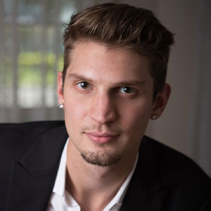 Headshot of young man with goatee, wearing a blazer
